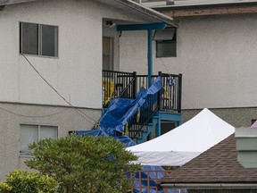 Tarps cover the rear staircase at a house in the 1700-block East 11th Avenue in Vancouver after a double murder shortly after midnight Tuesday.