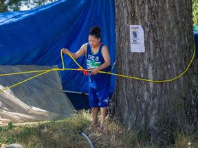 A woman adjusts a rope blocking a vehicle entrance to Strathcona park tent city.