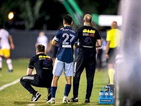 Vancouver Whitecaps rookie Ryan Raposo gets ready to check in the game against the San Jose Earthquakes on Wednesday while getting last-minute instructions from coaches Marc Dos Santos, left, and Philip Dos Santos, right.