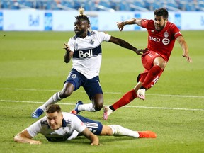 Toronto's Alejandro Pozuelo shoots over Vancouver's Leo Owusu and Jake Nerwinski  during the second half of Tuesday's game at BMO Field in Toronto.