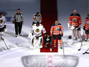 Malcolm Subban of the Chicago Blackhawks and Darnell Nurse of the Edmonton Oilers place their hands on Mathew Dumba of the Minnesota Wild during the national anthem of the United States before the Game One of the Eastern Conference Qualification Round prior to the 2020 NHL Stanley Cup Playoffs  at Rogers Place on August 01, 2020 in Edmonton, Alberta. Dumba spoke before the game about the NHL's support of Black Lives Matter and ending racism.