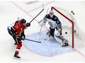 Milan Lucic #17 of the Calgary Flames takes a shot as Connor Hellebuyck #37 of the Winnipeg Jets defends in Game One of the Western Conference Qualification Round prior to the 2020 NHL Stanley Cup Playoffs at Rogers Place on August 01, 2020 in Edmonton, Alberta.