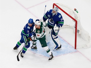 Troy Stecher #51 of the Vancouver Canucks and Joel Eriksson Ek #14 of the Minnesota Wild fight for position in front of Jacob Markstrom #25 in Game 2.