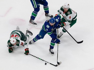 Chris Tanev #8 of the Vancouver Canucks battles for the puck against Ryan Donato #6 and Ryan Hartman #38 of the Minnesota Wild in Game 2.