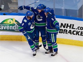 Brock Boeser of the Vancouver Canucks, right, celebrates his second-period goal on Tuesday with J.T. Miller, left, and Elias Pettersson. The Canucks tied the best-of-five qualifying series with a 4-3 win in Edmonton.