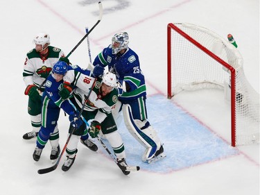 Jacob Markstrom #25 and Tyler Myers #57 of the Vancouver Canucks fight for position against Jordan Greenway #18 of the Minnesota Wild  in Game 2.