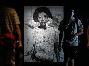 People walk past a photograph of 10-year-old atomic-bomb survivor Yukiko Fuji — who went on to have two children but died of cancer at the age of 42 — as they visit Hiroshima Peace Memorial Museum. August 6, 2020 marks the 75th anniversary of the atomic bombing of Hiroshima.