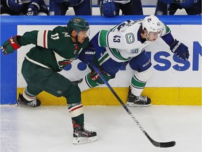 Minnesota Wild forward Zach Parise, left, and Vancouver Canucks defenceman Quinn Hughes chase a loose puck during the third period of Western Conference qualifying at Rogers Place on Aug. 6 in Edmonton.