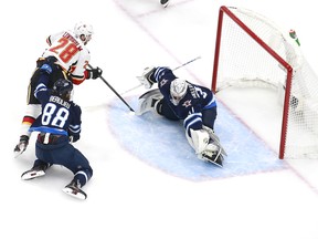 Elias Lindholm of the Calgary Flames scores on Winnipeg Jets goaltender Connor Hellebuyck during Game 3 of their Western Conference play-in series on Tuesday.