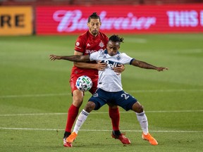 Aug 18, 2020; Toronto, Ontario, CAN; Vancouver Whitecaps forward Yordi Reyna (29) battles for the ball against Toronto FC defender Omar Gonzalez (44) during the first half at BMO Field. Mandatory Credit: Kevin Sousa-USA TODAY Sports