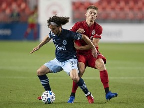 Whitecaps midfielder Russell Teibert shields the ball from Toronto FC midfielder Liam Fraser during their Major League Soccer Canadian Series match on Aug. 21, 2020 at BMO Field in Toronto.