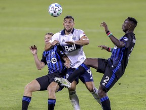 Vancouver Whitecaps forward Lucas Cavallini splits Montreal Impact midfielder Samuel Piette, left, and Victor Wanyama during their game in Montreal last Tuesday.
