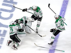 Jason Dickinson and Mattias Janmark of the Dallas Stars grab on to Anton Khudobin as they celebrate their 3-2 overtime victory against the Vegas Golden Knights to win Game Five of the Western Conference Final during the 2020 NHL Stanley Cup Playoffs at Rogers Place on September 14, 2020 in Edmonton, Alberta, Canada.