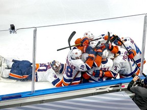 Jordan Eberle of the New York Islanders is congratulated by his teammates as Semyon Varlamov dives toward the team after scoring the game-winning goal against the Tampa Bay Lightning during the second overtime period to win Game Five of the Eastern Conference Final during the 2020 NHL Stanley Cup Playoffs at Rogers Place on September 15, 2020 in Edmonton, Alberta, Canada.