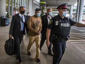 A handcuffed Henry Morales is escorted into custody after landing at Pearson International Airport.