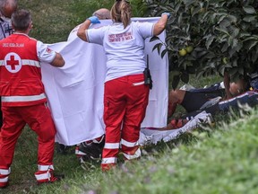 Rescuers hold a sheet as other rescuers tend to cyclist Chloe Dygert Owen (lying at R) after she fell during the Women's Elite Individual Time Trial at the UCI 2020 Road World Championships in Imola, Emilia-Romagna, Italy, Thursday, Sept. 24, 2020.