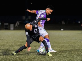 Pacific FC midfielder Matthew Baldisimo tussles with his Atletico Ottawa counterpart. Francisco Acuna Víctor, during Wednesday's game.