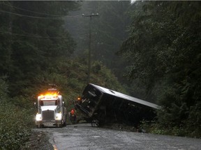 A tow-truck crew removes a bus from an embankment next to a logging road near Bamfield, B.C., on Saturday, Sept. 14, 2019. Improvements are coming to a narrow logging road on Vancouver Island that has taken the lives of many members of the local First Nations as well as two university students last year.