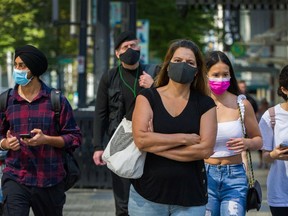 People wear masks to protect against COVID-19 at Granville and Georgia streets in Vancouver.