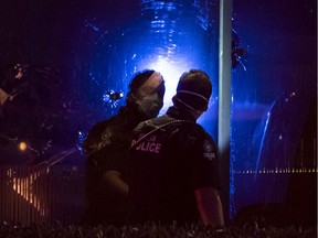 A member of the Delta Police looks at a bullet hole in the window of Manzo Japanese Restaurant where two people were shot at in Richmond on the night of Sept. 18, 2020.