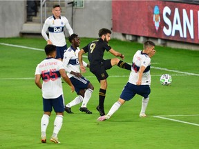 Los Angeles FC forward Diego Rossi (9) takes a shot on goal against the defence of Vancouver Whitecaps defender Ranko Veselinovic (4) during the first half Wednesday at Banc Of California Stadium.