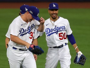 Mookie Betts, right, celebrates with Cody Bellinger and Joc Pederson after the Los Angeles Dodgers' 3-1 victory against the Atlanta Braves in Game 6 of the NLCS at Globe Life Field in Arlington, Texas, on Saturday.