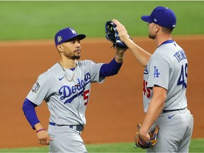 Mookie Betts #50 and Blake Treinen #49 of the Los Angeles Dodgers celebrate the teams 4-2 victory against the Tampa Bay Rays in Game Five of the 2020 MLB World Series at Globe Life Field on October 25, 2020 in Arlington, Texas.