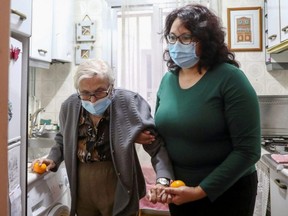 Florentina Martin, a 99 year-old woman who survived COVID-19, is helped by her caregiver Olga Arauz in her home in Pinto, near Madrid, Spain, Tuesday, Oct. 20, 2020.