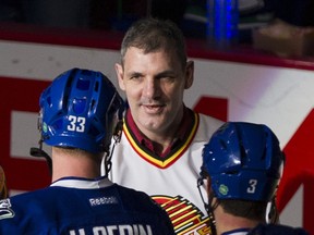 Former Vancouver Canucks player Gino Odjick shakes hands with Henrik Sedin before a fan-appreciation game at Rogers Arena on April 11, 2015.