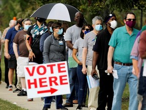 Voters wait in line to enter a polling place and cast their ballots on the first day of the state's in-person early voting in Durham, N.C., on Oct. 15, 2020.