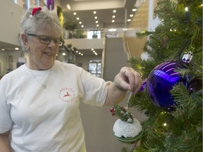 Velma MacAllister, head volunteer of the Langley Christmas Bureau, hangs a decorative ball on the Christmas tree at Langley City Hall on Nov. 17.