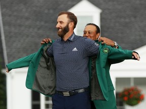 Dustin Johnson gets some help from last year's Masters champion, Tiger Woods, in pulling on the fabled green jacket after winning the 2020 Masters golf tournament at Augusta National Golf Club in Augusta, Ga., on Nov. 15, 2020.