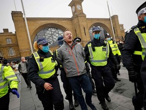 Police officers wearing protective face coverings to combat the spread of the coronavirus covid-19 take away a protester ahead of an anti-lockdown protest against government restrictions designed to control or mitigate the spread of the novel coronavirus, including the wearing of masks and lockdowns, at Kings Cross station in London on November 28, 2020.