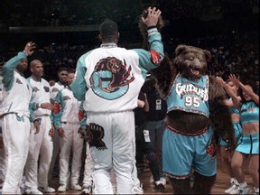 The Grizz mascot high-fives Vancouver Grizzlies players before the team's home opener at GM Place.