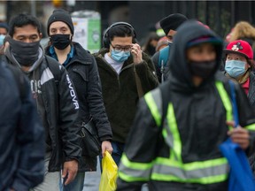 People wearing masks near Commercial and Broadway Skytrain station in Vancouver