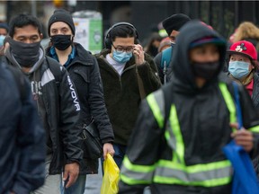 People wear masks near the Commercial and Broadway SkyTrain Station in Vancouver.