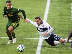 Nov 1, 2020; Portland, Oregon, USA; Portland Timbers defender Pablo Bonilla (28) steals the ball away from Vancouver Whitecaps midfielder Russell Teibert (31) during the first half at Providence Park. Mandatory Credit: Troy Wayrynen-USA TODAY Sports