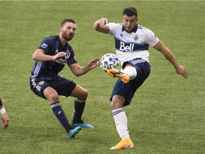 Vancouver Whitecaps forward Lucas Cavallini passes the ball against Los Angeles Galaxy defender Perry Kitchen during the first half at Providence Park on Sunday.