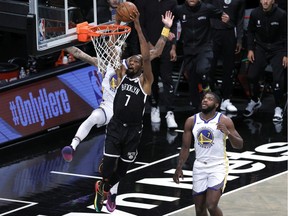 Kevin Durant of the Brooklyn Nets dunks as Kelly Oubre Jr. and Eric Paschall of the Golden State Warriors defend during the first half at Barclays Center on December 22, 2020 in the Brooklyn borough of New York City.