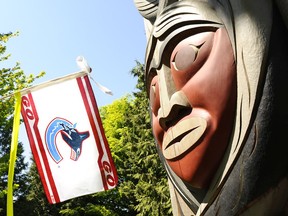 A Canucks fan flag — featuring the orca logo — faces off against one of the First Nations totem poles in Stanley Park in 2011.
