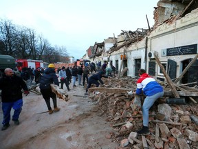 People clean debris after an earthquake, in Petrinja, Croatia December 29, 2020.