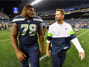 D.J. Fluker and Offensive Coordinator Brian Schottenheimer of the Seattle Seahawks walk off the field after a victory against the Denver Broncos preseason game at CenturyLink Field on August 08, 2019 in Seattle, Washington.