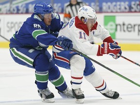 Vancouver Canucks defenceman Nate Schmidt (88) fights for control of the puck with Montreal Canadiens right wing Brendan Gallagher (11) during first period NHL action in Vancouver, Thursday, January 21, 2021.