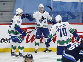 Vancouver Canucks' Bo Horvat (53), Nils Hoglander (36) and Tanner Pearson (70) celebrate Hoglander's goal against Winnipeg Jets goaltender Connor Hellebuyck (37) during first period NHL action in Winnipeg on Saturday.