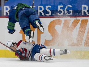 Vancouver Canucks defenceman Jordie Benn checks Montreal Canadiens forward Nick Suzuki Saturday at Rogers Arena.