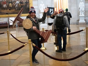 A pro-Trump protester carries the lectern of U.S. Speaker of the House Nancy Pelosi through the Roturnda of the U.S. Capitol Building on January 6, 2021 in Washington.