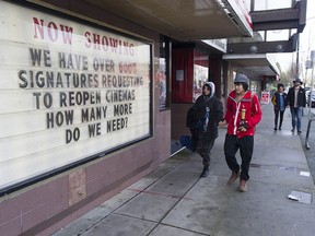 Passersby walk past a sign at the Rio Theatre on E. Broadway in Vancouver questioning why their business is closed due to Covid-19 restrictions, Friday, January 15, 2021.