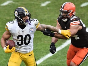 Pittsburgh Steelers running back James Conner (left) runs with the ball as Cleveland Browns defensive end Olivier Vernon defends on Jan. 3, 2021 at FirstEnergy Stadium.