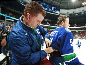 Vancouver Canucks assistant equipment manager Brian Hamilton adjusts Derek Dorsett's equipment before an NHL game.
