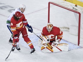 Flames goalie Jacob Markstrom and teammate Chris Tanev, here blocking out Canuck Tanner Pearson during their game in Calgary last month, are two of the three former Canucks returning to Vancouver to face their former team starting Thursday.